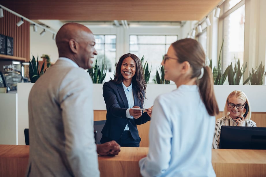 2 women and 1 man talking and smiling, in business attire